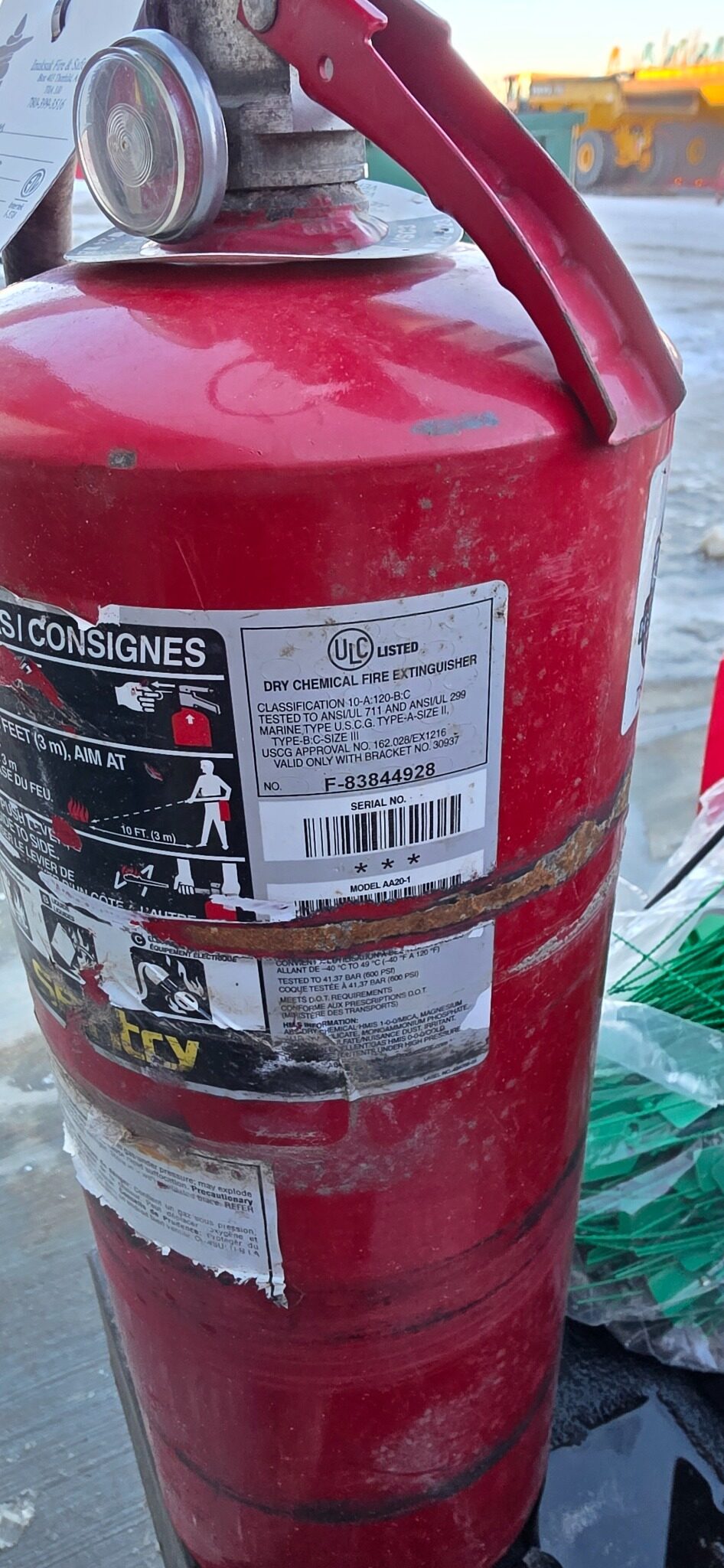 Fire extinguisher serial number F-83844928 with hose band damage — near-miss label destruction, Northern Alberta field inspection