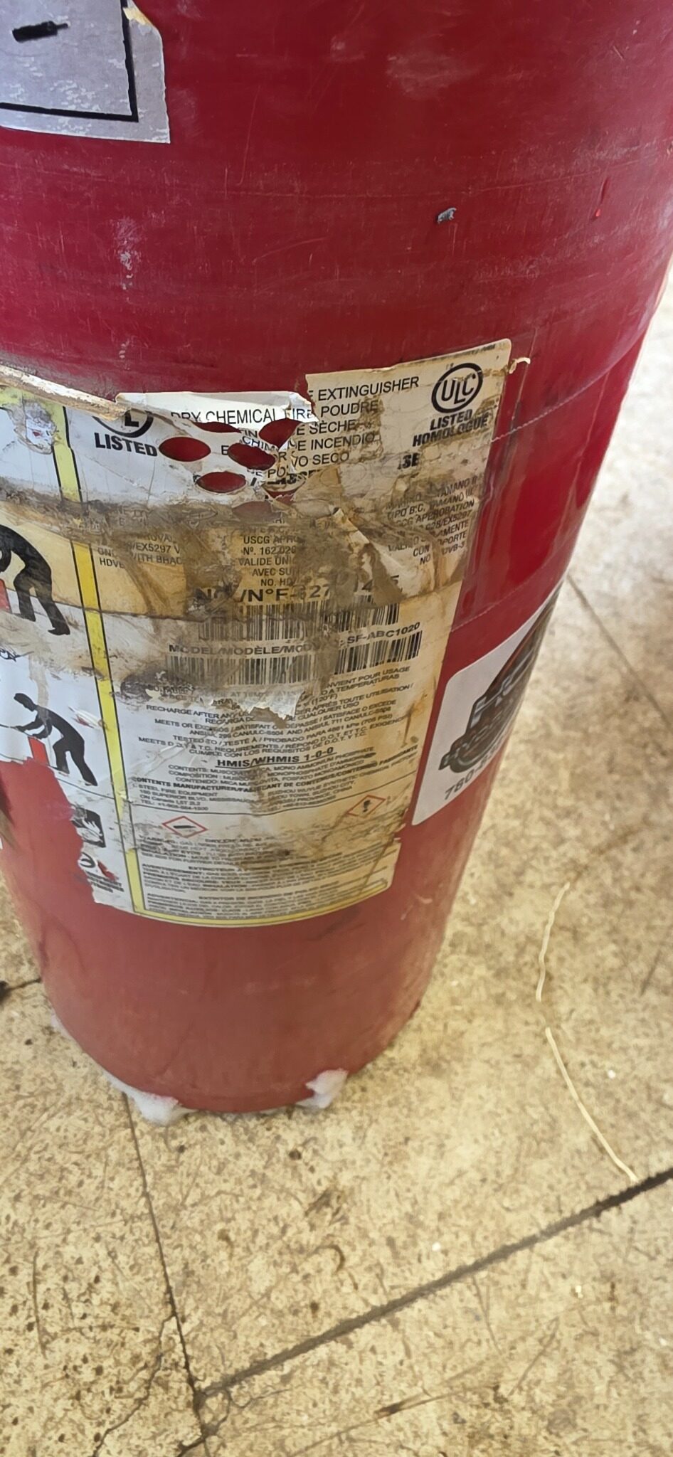 Fire extinguisher with severely peeling and damaged label — real field photo from Northern Alberta inspection